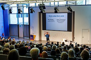 Voller Hörsaal beim Vortrag von Prof. Beck, der vorne spricht.